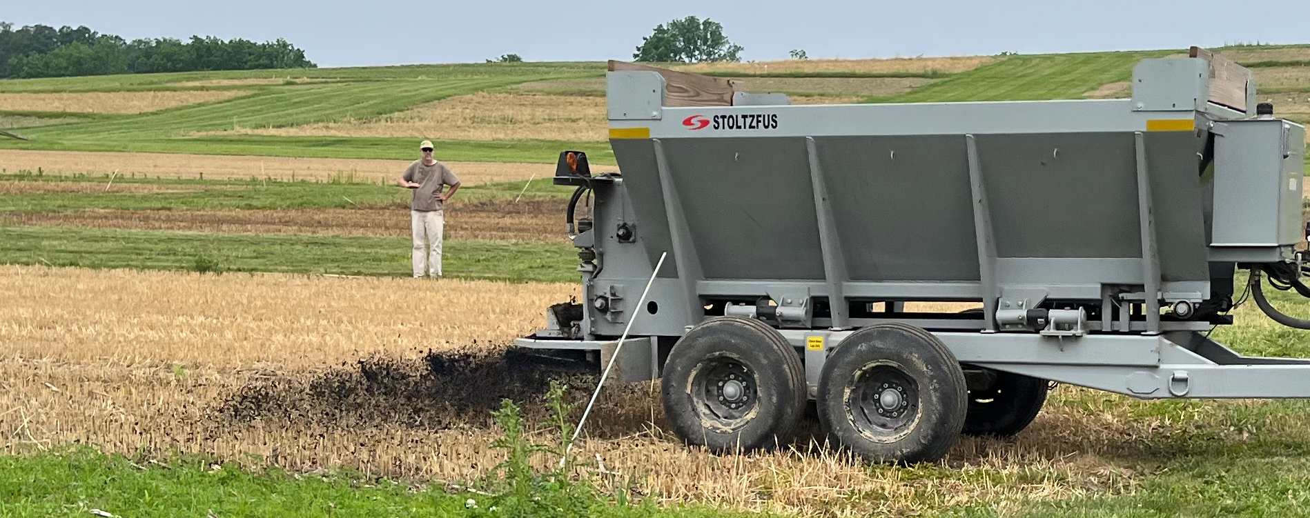 A spreader applying biochar across research plots with retained crop residue